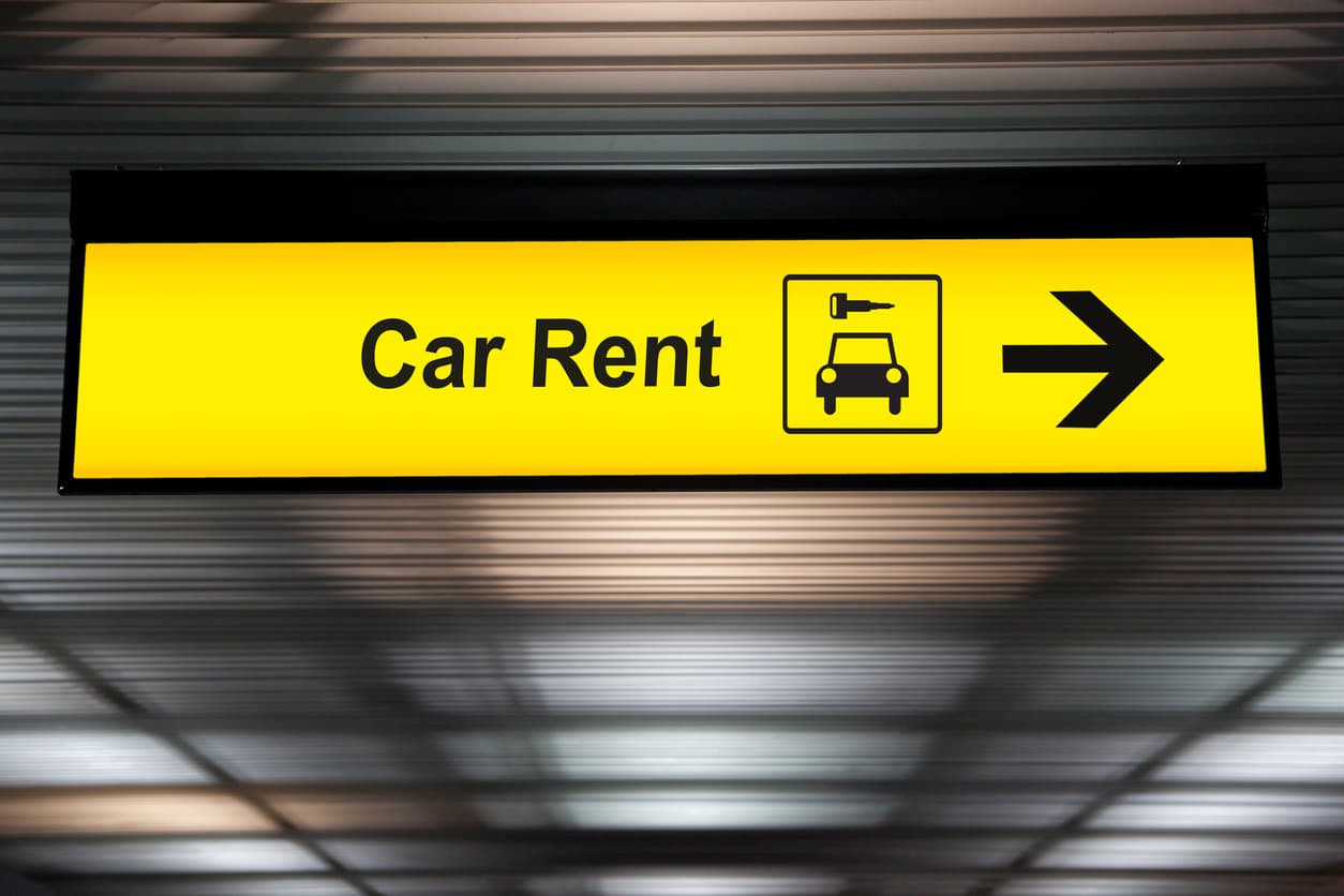 Yellow sign reading “Car Rent” in black with a location arrow