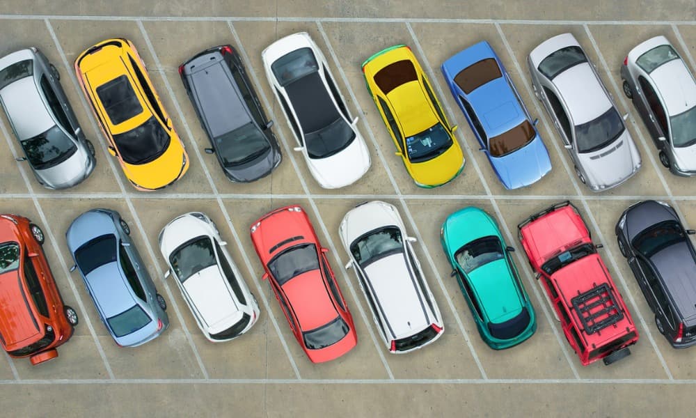 An overhead photograph of many different colored cars in a parking lot.
