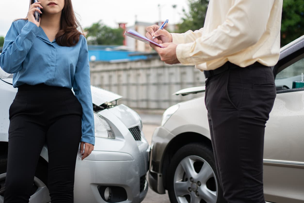 A man and a woman exchanging insurance information after a car accident.