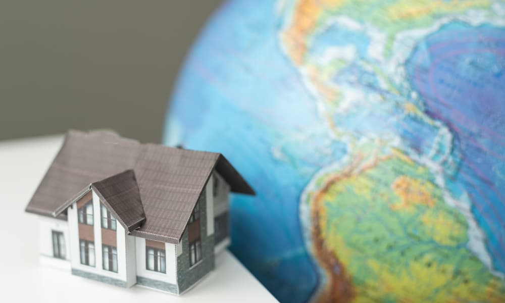 A model of a home with a large earth globe behind it.