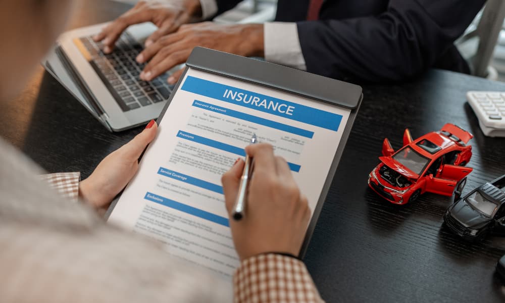 A man reviewing an auto insurance policy at a desk with model cars.