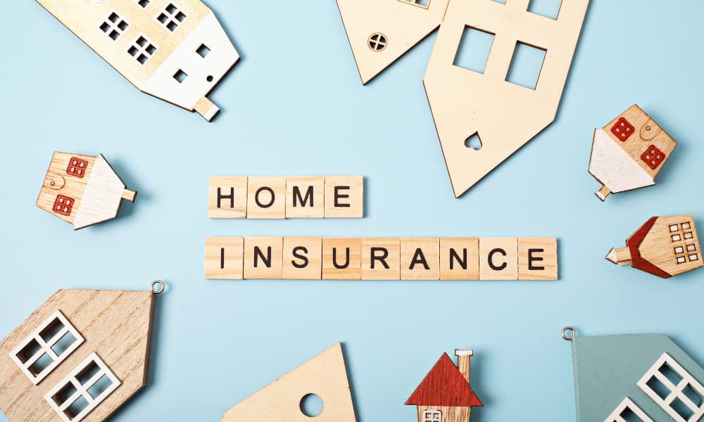 what-is-new-york-homeowners-insurance-why-do-i-need-it Wooden blocks spelling “home insurance” surrounded by wooden houses on a blue background.