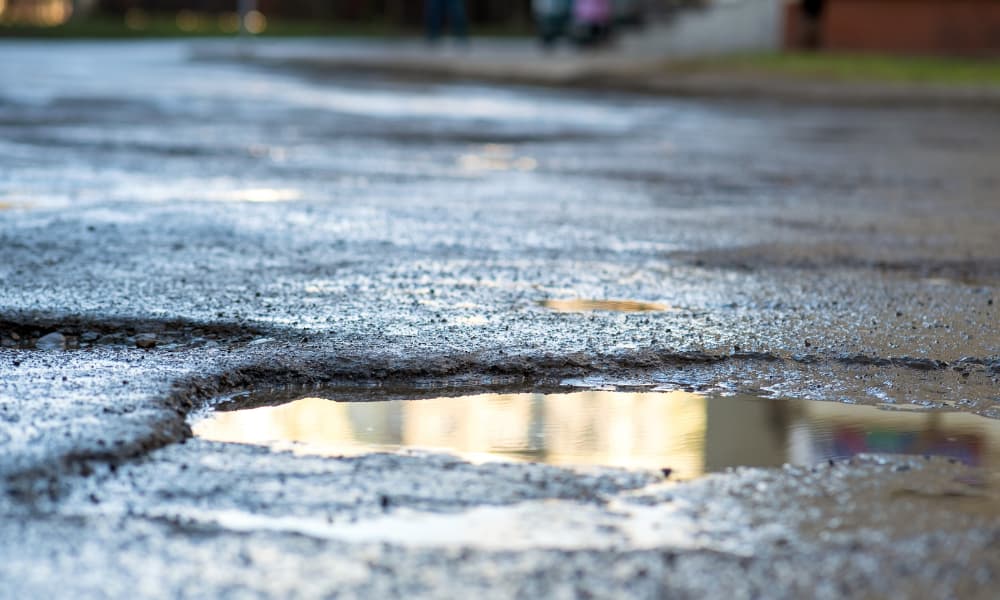 A close-up of a large pothole in a wet road.