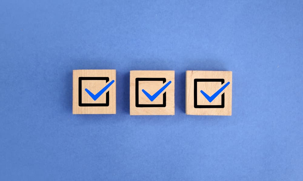 Three wooden blocks with blue check marks set on a blue background.
