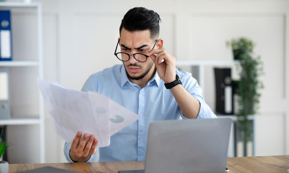 An annoyed man staring at home insurance documents.