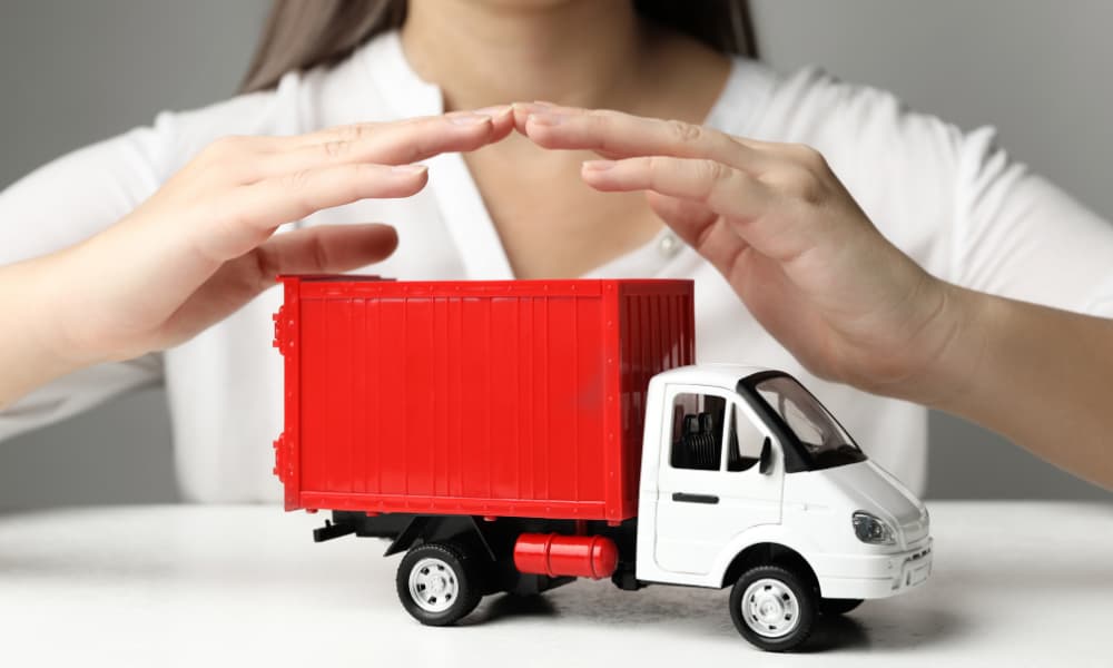 Hands protecting a toy truck to represent commercial auto insurance coverage