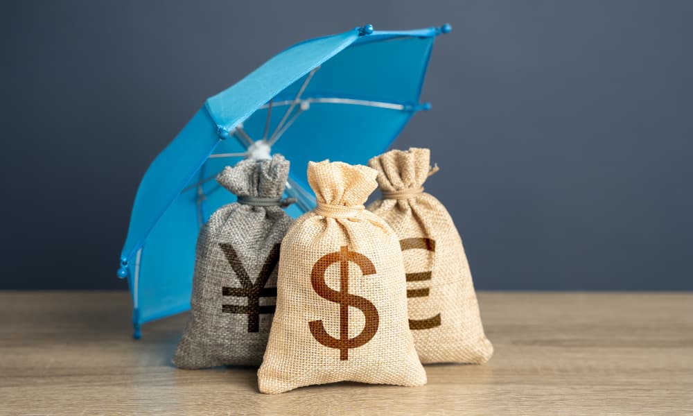 Three small fabric bags on a wooden table against a blue umbrella.